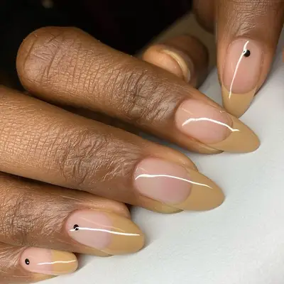 Neutral acrylic nails with black dot on three of the nails