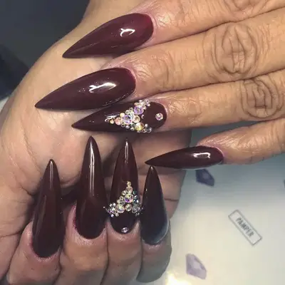 Acrylic nails in oxblood with statement sequins on one nail