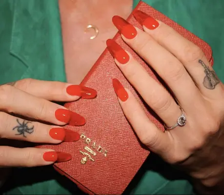 Long red jelly acrylic nails holding red Prada wallet