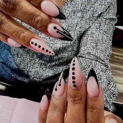 Person with sharp acrylic nails with black French tip and dotted designs