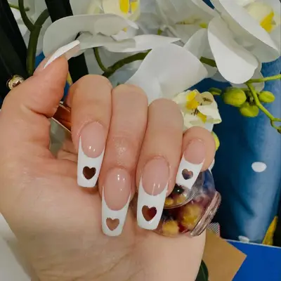 Person with heart-shaped cutouts in white French tip acrylic nails