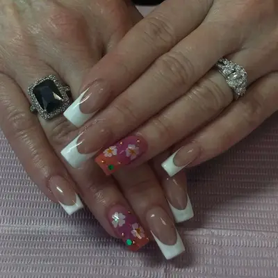 Person with white acrylic French tips and floral ring finger nail design
