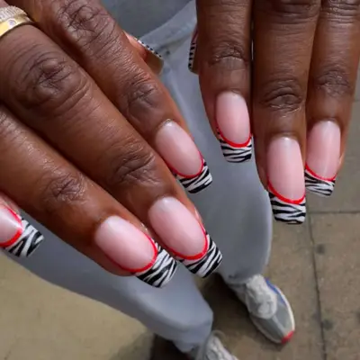 French manicure with zebra-printed tips and a red outline.