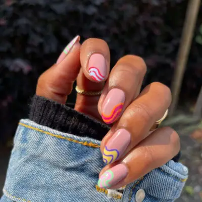 French manicure-inspired nail look with tips covered in diagonal waves in different colors.