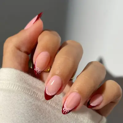 French manicure with burgundy tips and pink bows.