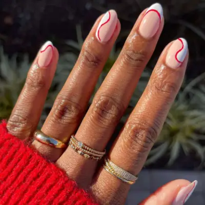 Swirls and French tips manicure with white, red, and cream.