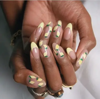 Close-up of hands with lemon-themed nail art design