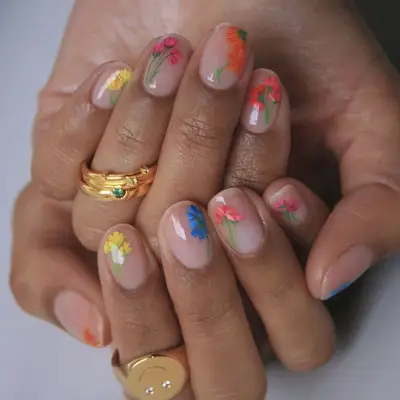 Close-up of hands with floral nail art and gold rings