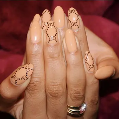 Hands with fingernails decorated with a repeating small logo pattern design