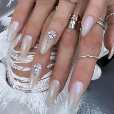 Vanilla chrome manicure with bejeweled accents and silver rings