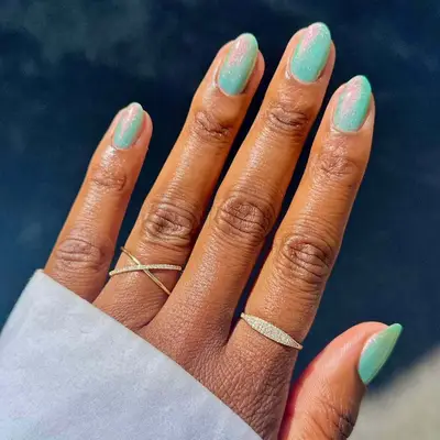 model with shimmery green nails with pink and orange shift