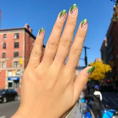 Clear nails with green sparkly diagonal corners and red dotted diagonal stripes