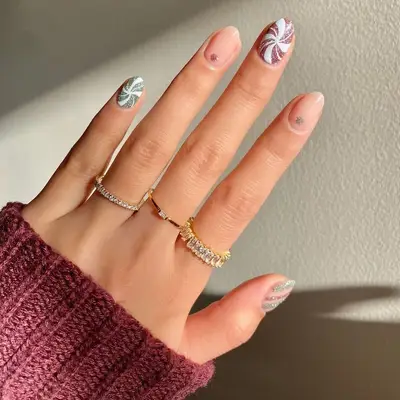 Eclectic Christmas nails with muted red and green glitter peppermint spirals, stripes, and dots