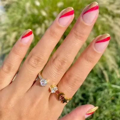 Clear manicure with gold and red diagonal corner detail