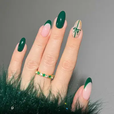 manicure with dark green christmas nails, one nail gold wrapped as present with bow