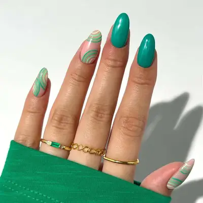 a green manicure with swirl accents