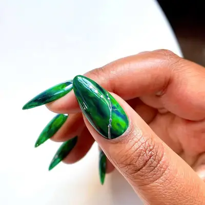 an emerald watercolor manicure with navy accents and silver chrome line nail art