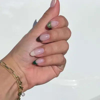 Close up of a French skittle manicure in shades of green and cream