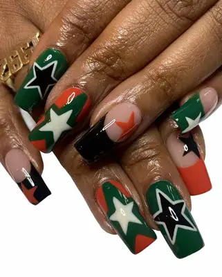 Close up of a manicure with star details in shades of black, orange, and green