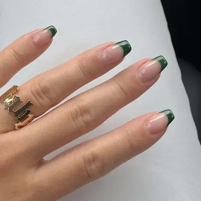 A French manicure with deep green, squared-off tips