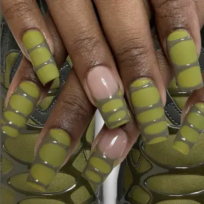 A textured green manicure, hands crossed over matching sneakers