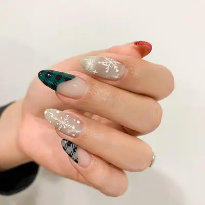 Close-up of manicure with red, green, and gray gingham abstract tips plus snowflake designs