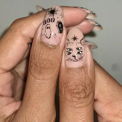 Tattoo-esque nail art with a ghost, a cat with four eyes, and a cobs web.