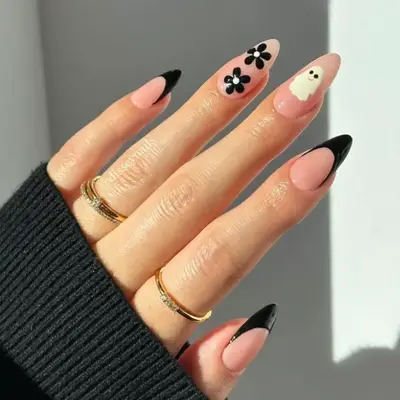 Black French manicure with an accent nail with black flowers and another accent nail with a smiling ghost.