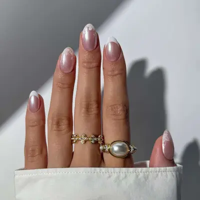 Hand with floral-designed fingernails and wearing three rings, including a pearl ring