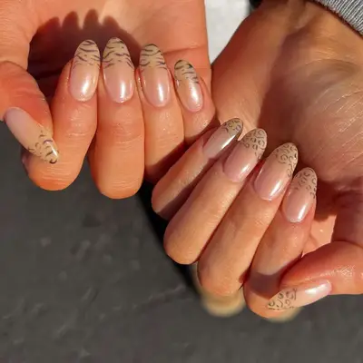 Hands displaying nails with minimalist French tips and animal-print designs