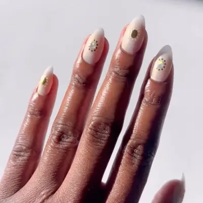 A hand displaying manicured nails with minimalist decorative gold accents