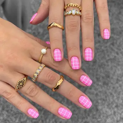 A manicure with a bubblegum pink base and white grids