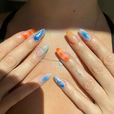 Bold mismatch nails featuring blue and orange with silver chrome swirls