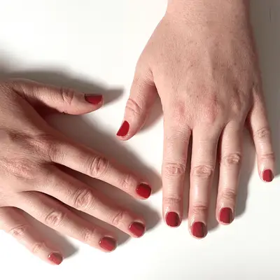 shot of hands against a white background showing red nails