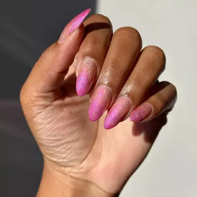 Hand with glitter peach and pink gradient manicure.