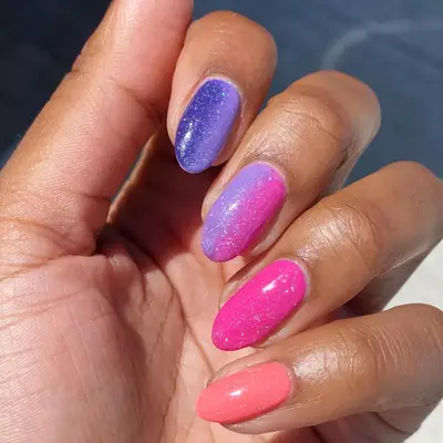 Hand with a dark purple to pink to peach gradient manicure