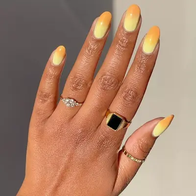 Hand with yellow and light orange gradient manicure.