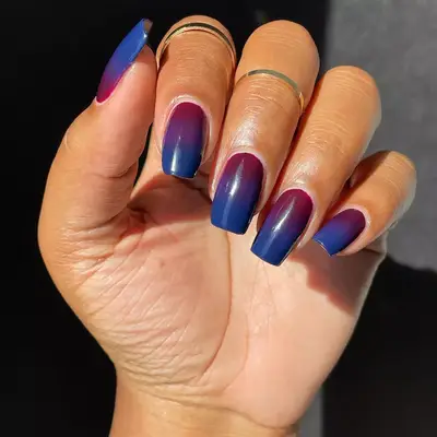 Hand with dark purple to navy blue gradient ombre manicure