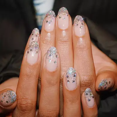 Hand with silver glitter ombre nails with star confetti