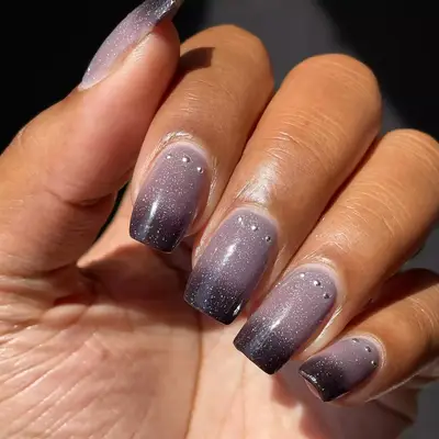 Hand with light mauve to dark purple gradient with silver studs at the cuticle