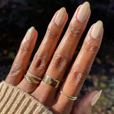 Hand with a gold glitter ombre manicure