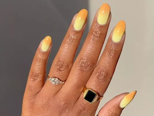 Hand with yellow and light orange ombre manicure