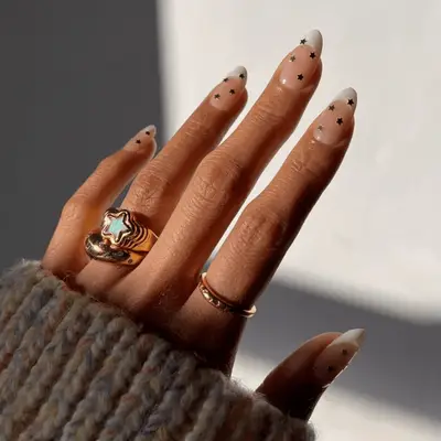 Almond shaped nails with classic French manicure and gold star decals