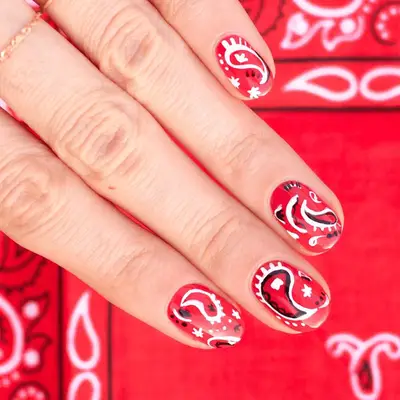 A close up of red short nails with a bandana print, paisley design