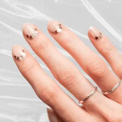 Close up of nude short nails with gold stars at the cuticle
