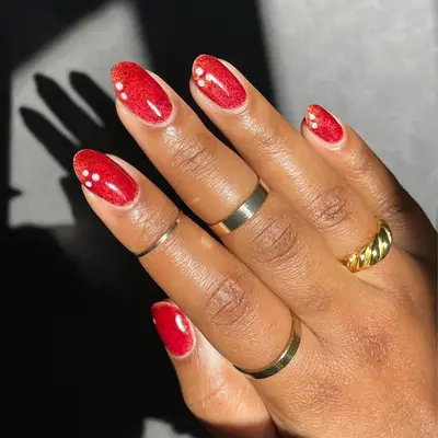 Hand with red decorated nails and gold rings