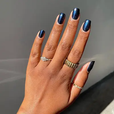 Hand with neatly manicured fingernails wearing rings on three fingers, close detail to the nails and jewelry