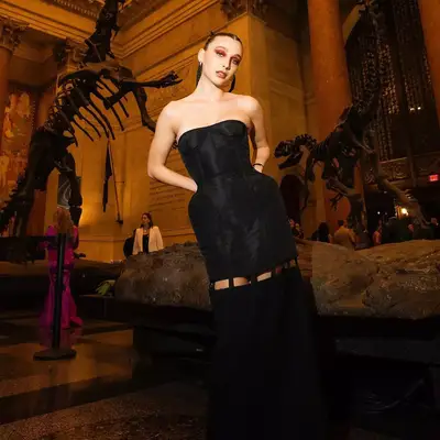 Emma chamberlain at the CFDA awards in a black dress, red eye makeup, and slicked back hair