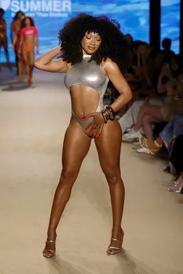 Megan Thee Stallion poses on the runway to show off her manicure and dark hair.