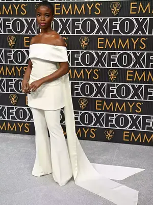 Joy Sunday wears a white off-shoulder top with cape and flared pants to the January 2024 Emmys